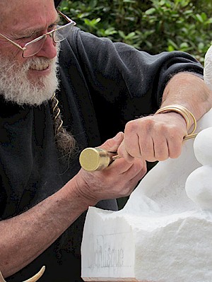 Fisher delicately chisels into a piece at the 2014 Art in the Gardens